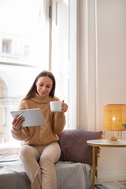 Foto gratuita donna del colpo pieno che assorbe l'ipad