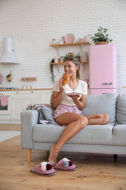 Free photo full shot woman eating croissant