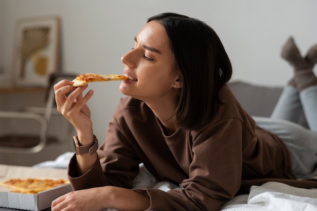 Free photo full shot woman eating delicious pizza