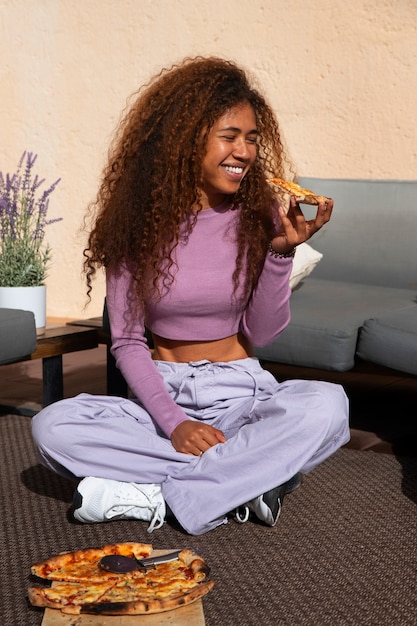 Free photo full shot woman eating delicious pizza