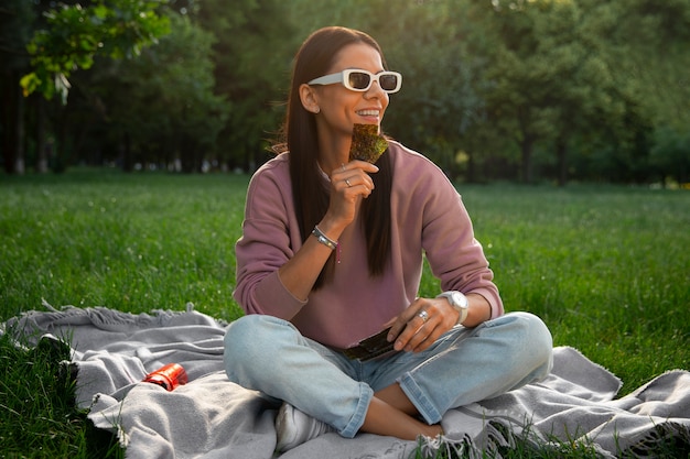 Free photo full shot woman  eating seaweed snack