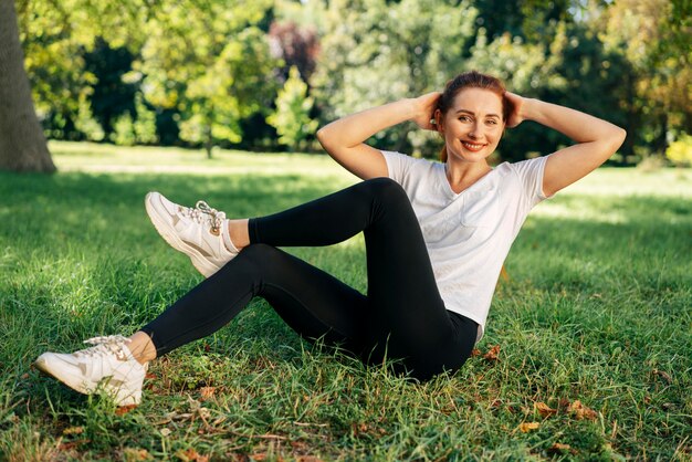 Full shot woman exercising on grass