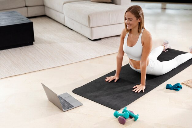 Full shot woman exercising on mat