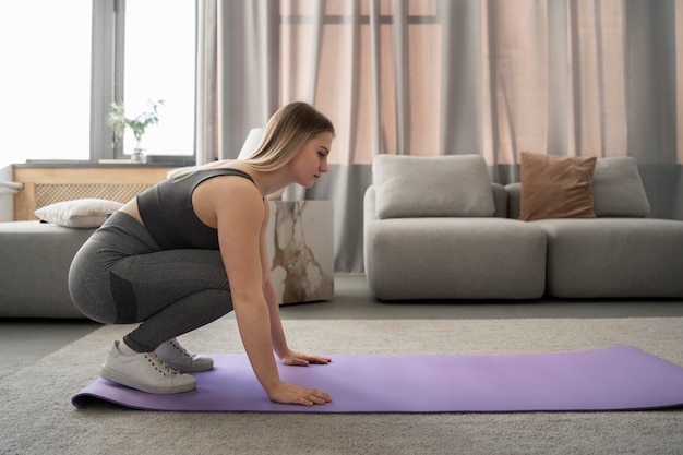 Full shot woman exercising on mat