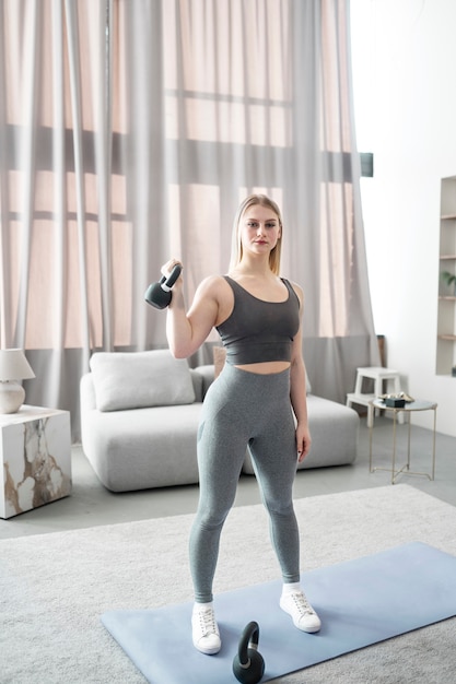 Free photo full shot woman exercising with kettlebell