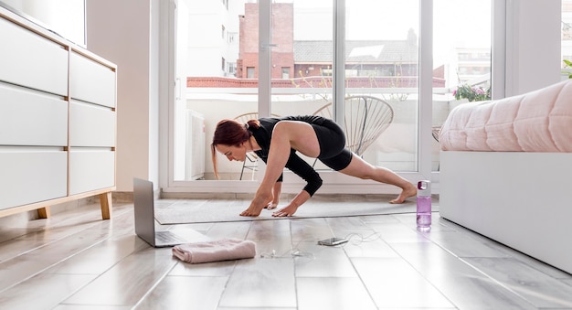 Full shot woman exercising with laptop