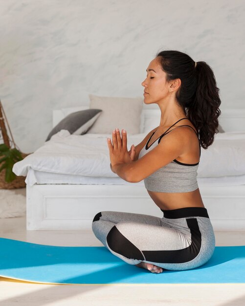 Full shot woman exercising on yoga mat