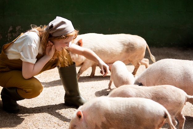 Full shot woman feeding pigs