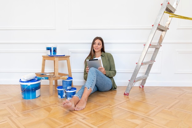 Full shot woman on floor holding tablet