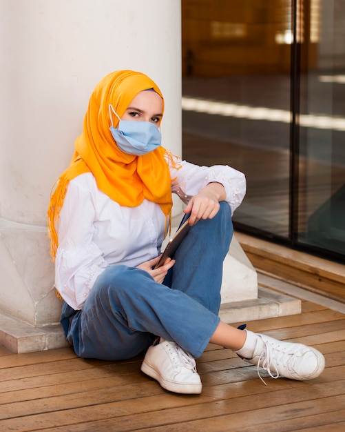 Full shot woman on floor wearing mask