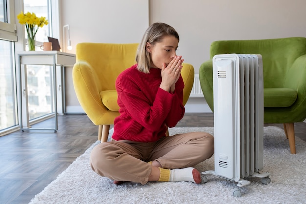 Full shot woman getting warm near heater