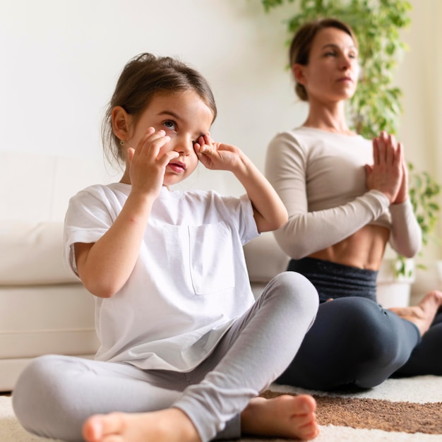 Full shot woman and girl exercising on floor