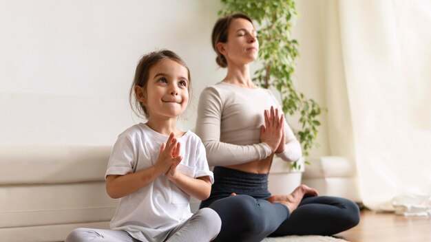 Full shot woman and girl meditating