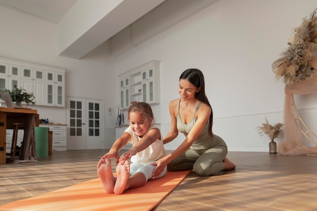 Free photo full shot woman helping kid stretch