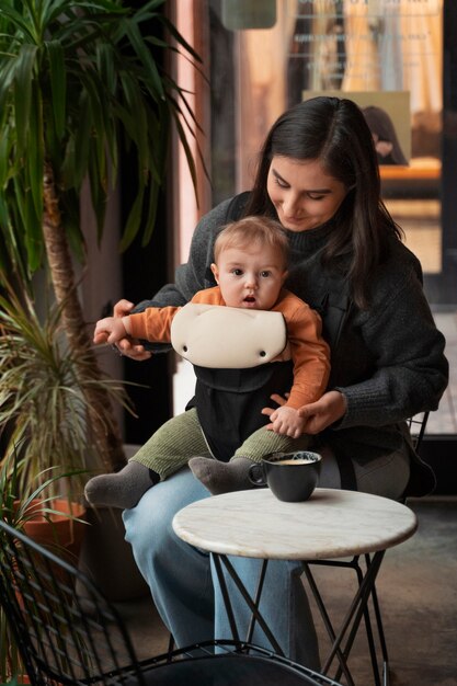 Full shot woman holding baby in carrier