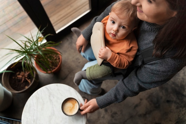 Free photo full shot woman holding baby in carrier