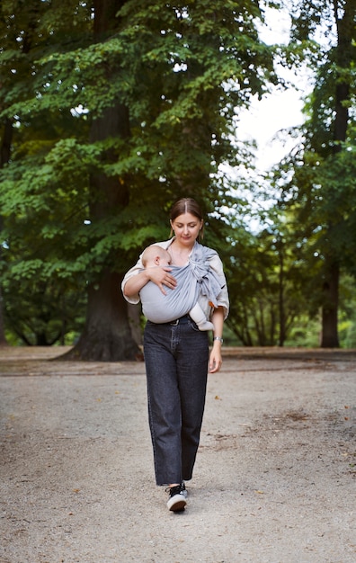 Foto gratuita bambino della holding della donna del colpo pieno all'aperto