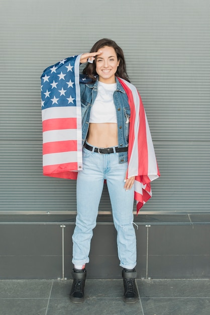 Полная съемка женщина держит большой флаг США и салютов