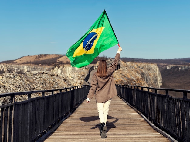 Free photo full shot woman holding brazilian flag