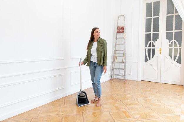 Full shot woman holding broom