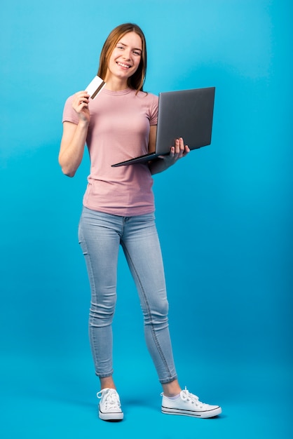 Full shot woman holding credit card and laptop