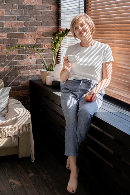 Full shot woman holding cup and apple