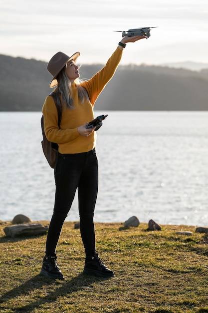 Free photo full shot woman holding drone outside