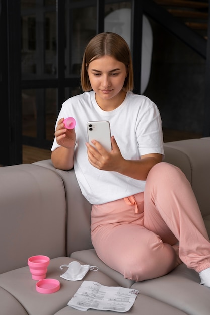 Donna del colpo pieno che tiene tazza mestruale