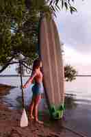 Foto gratuita donna a tutto campo che tiene il paddleboard