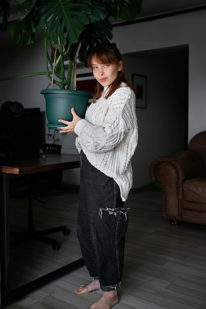 Full shot woman holding plant pot