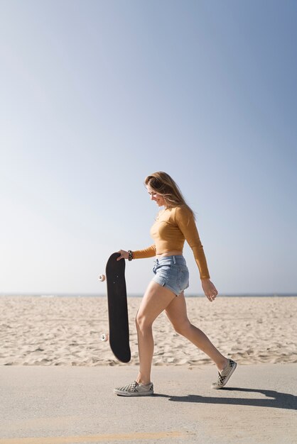 Full shot woman holding skateboard