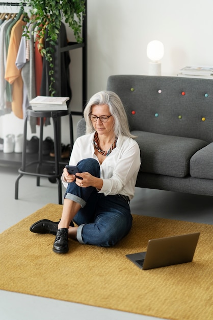 Full shot woman holding smartphone on floor