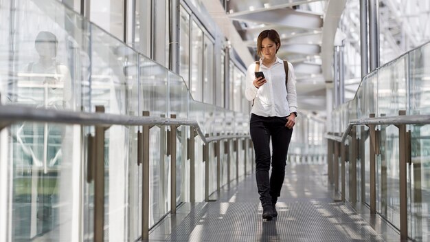 Full shot woman holding smartphone