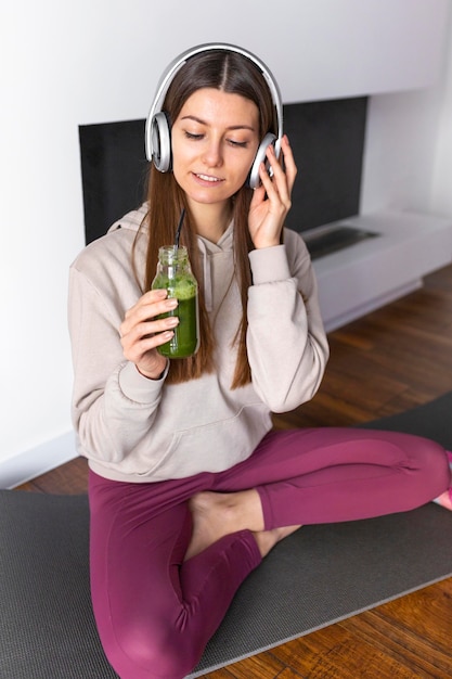 Full shot woman holding smoothie bottle