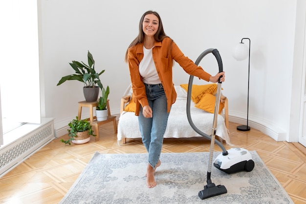 Full shot woman holding vacuum cleaner