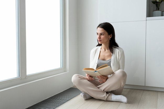 Full shot woman at home with book