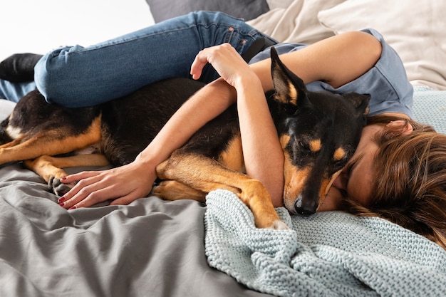 Полный снимок женщина обнимает собаку в постели