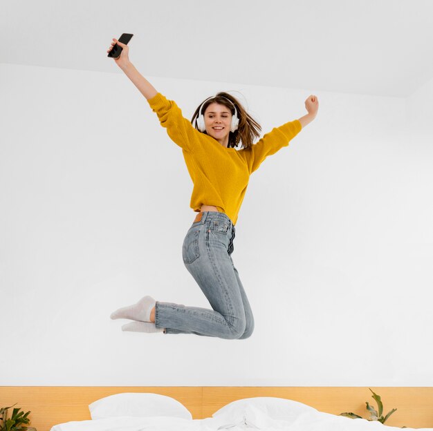ベッドでジャンプするフルショットの女性