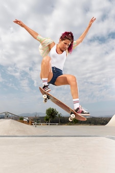 Full shot woman jumping with skateboard