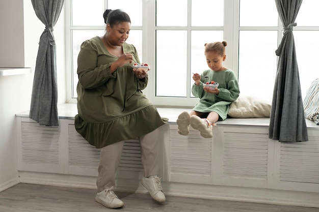 Full shot woman and kid eating