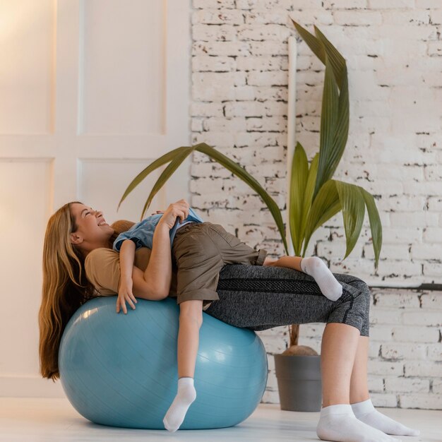 Full shot woman and kid on gym ball