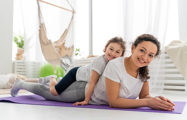 Full shot woman and kid on mat