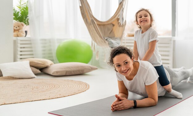 Full shot woman and kid on mat