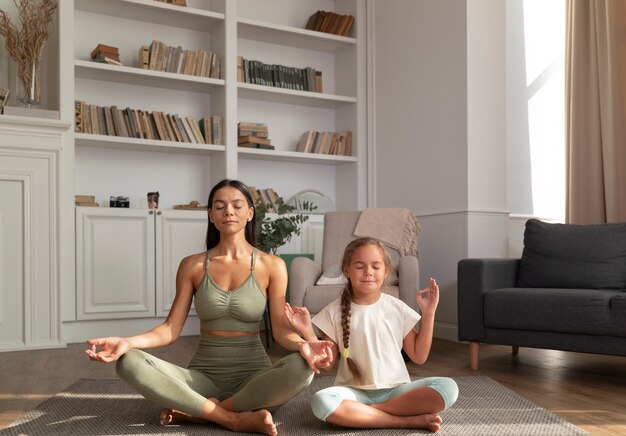 Full shot woman and kid meditate