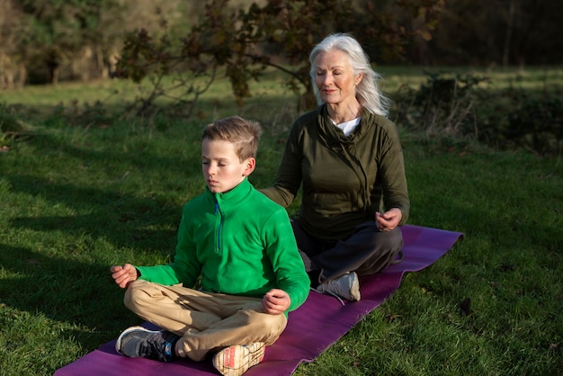 Full shot woman and kid meditating