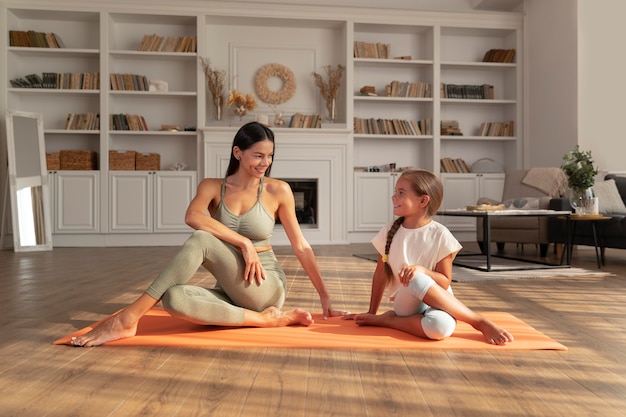 Женщина и ребенок в полный рост на коврике для йоги