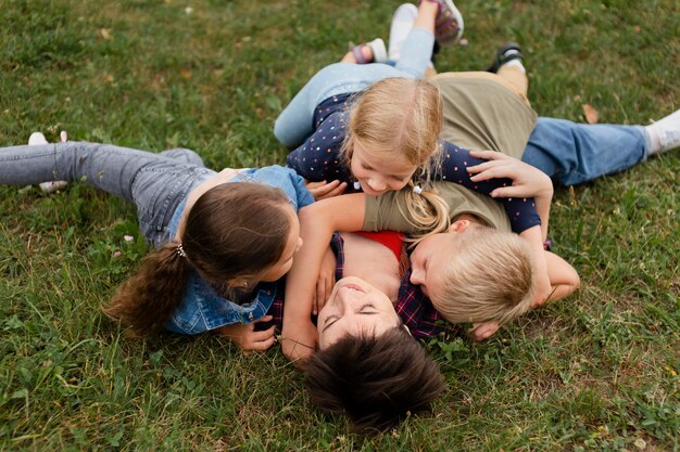 Full shot woman and kids laying on grass