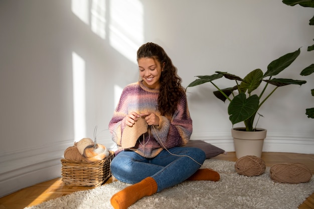 Full shot woman knitting on floor