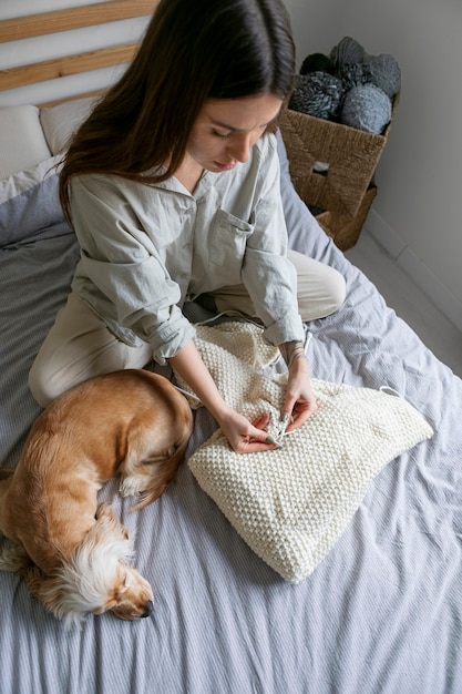 Full shot woman knitting at home with dog