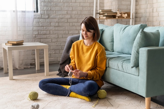 Free photo full shot woman knitting at home